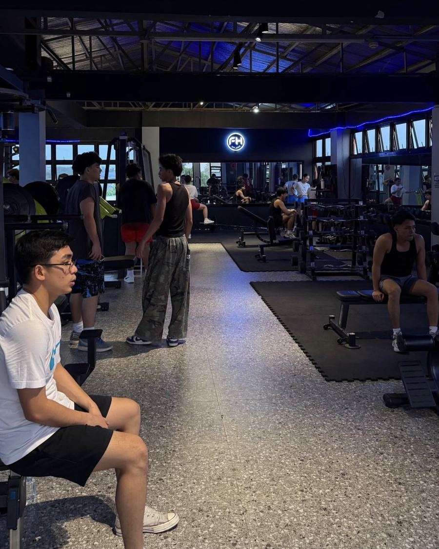 The main training floor with dumbbell racks and the lit FH sign